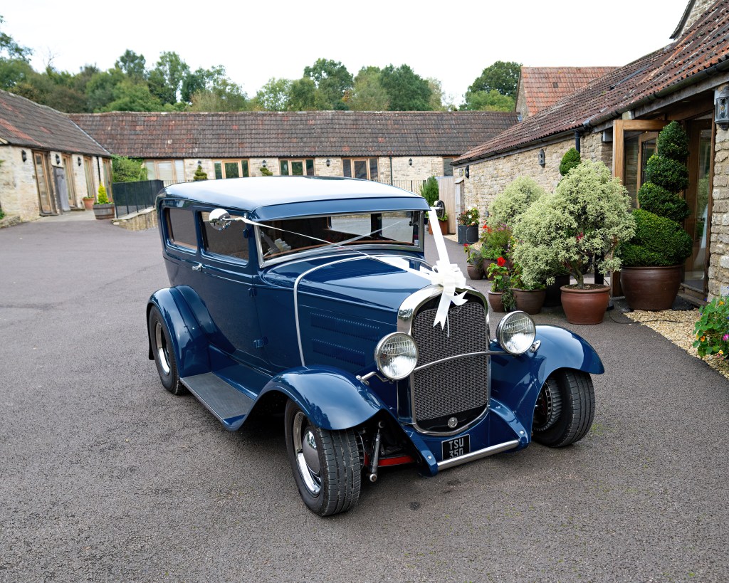 Scene of wedding dressing up hired antique classic car. Outdoor. Not people appear. Garage/stable or shed building.